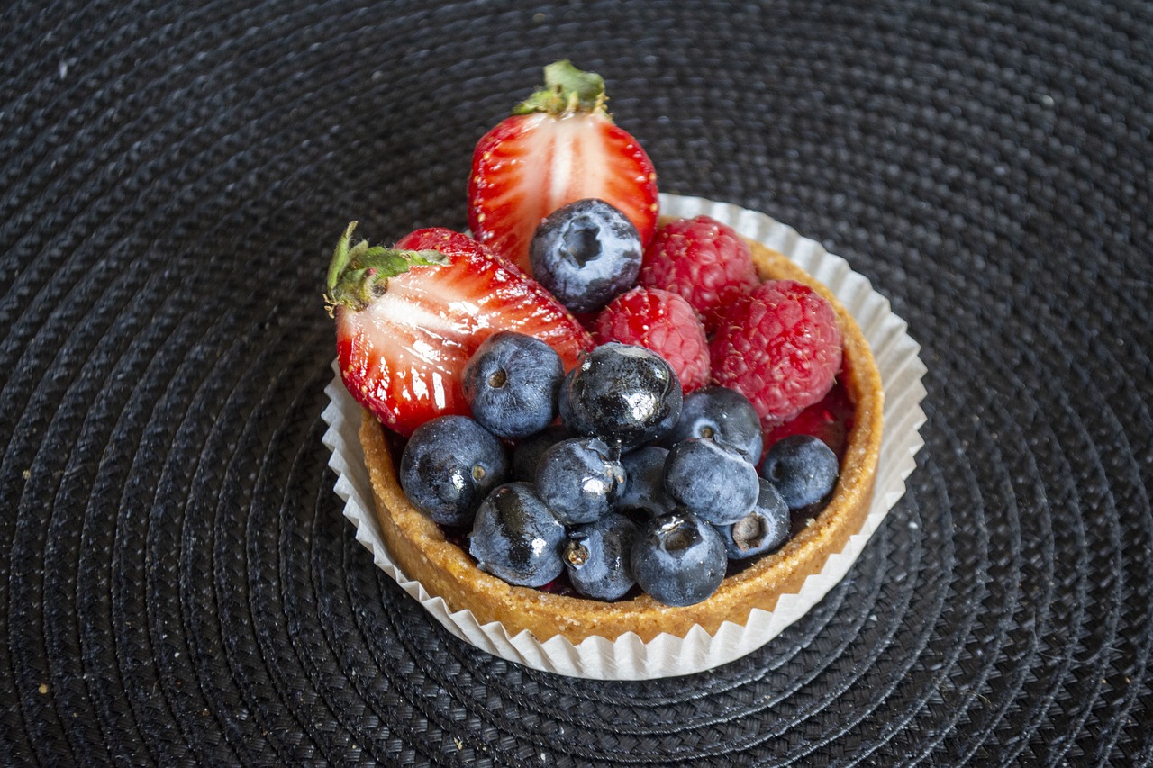 Crostata morbida alla frutta con colori vivaci, decorata con fette di frutta fresca su un piatto.